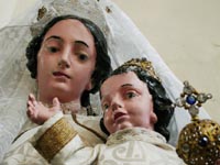 La Vierge habillée, semblable à tant d’autres, n’a jamais attiré l’attention de ceux qui ont étudié nos statues. Néanmoins, elle pourrait dater du XVIIIe siècle. Elle fait penser à N.-D. de Luxembourg, patronne de l’ancien Duché du même nom. L’humeur de Marie, un peu mélancolique, est remplie de réserve, de discrétion. L’Enfant-Jésus est enjoué; il lève fièrement le bras droit et pourtant on perçoit dans cette attitude de la retenue.