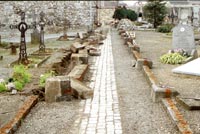 Les robustes grillages qui délimitaient l’allée nord du cimetière donnant accès à l’église viennent d’être enlevés. On distingue, éparses, les bordures en pierre de taille. 