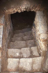 Escalier donnant accès à une petite cave voûtée.
